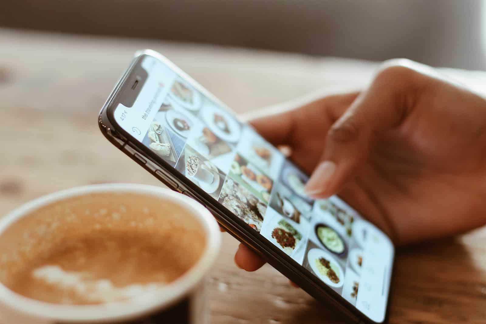Someone holding a phone with images on the screen ready to upload to their social media account, adding to their digital footprint.